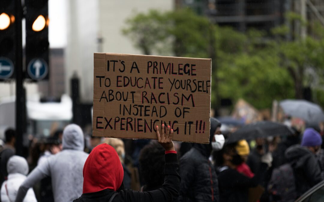 Photo by James Eades on Unsplash person holding signage that reads "It's a privilege to educate yourself about racism instead of experiencing it"